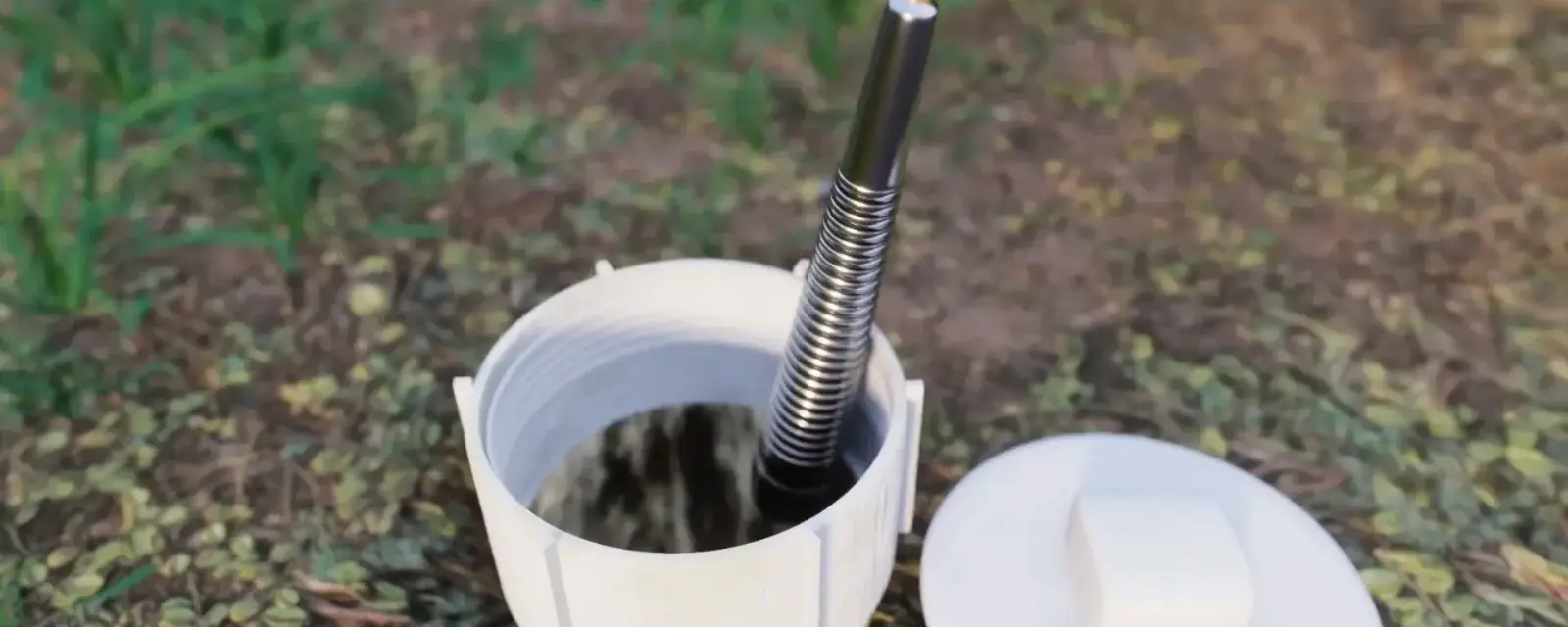 Camera cable feeding into a white capped sewer cleanout in a grassy yard